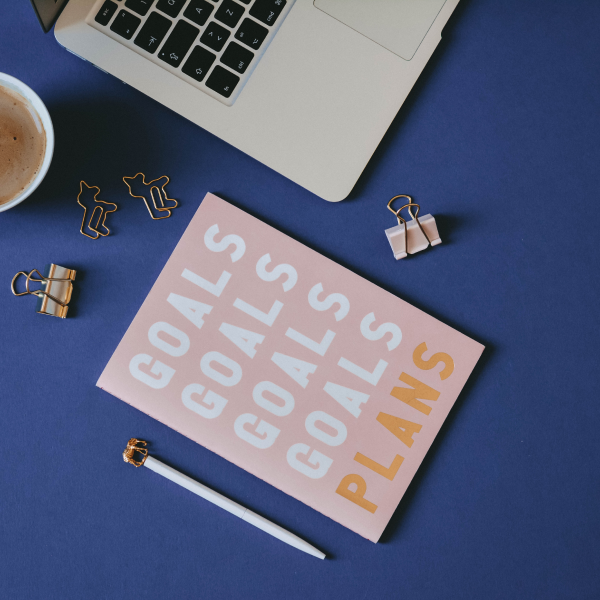 Desk setup with goals planner, laptop, and coffee